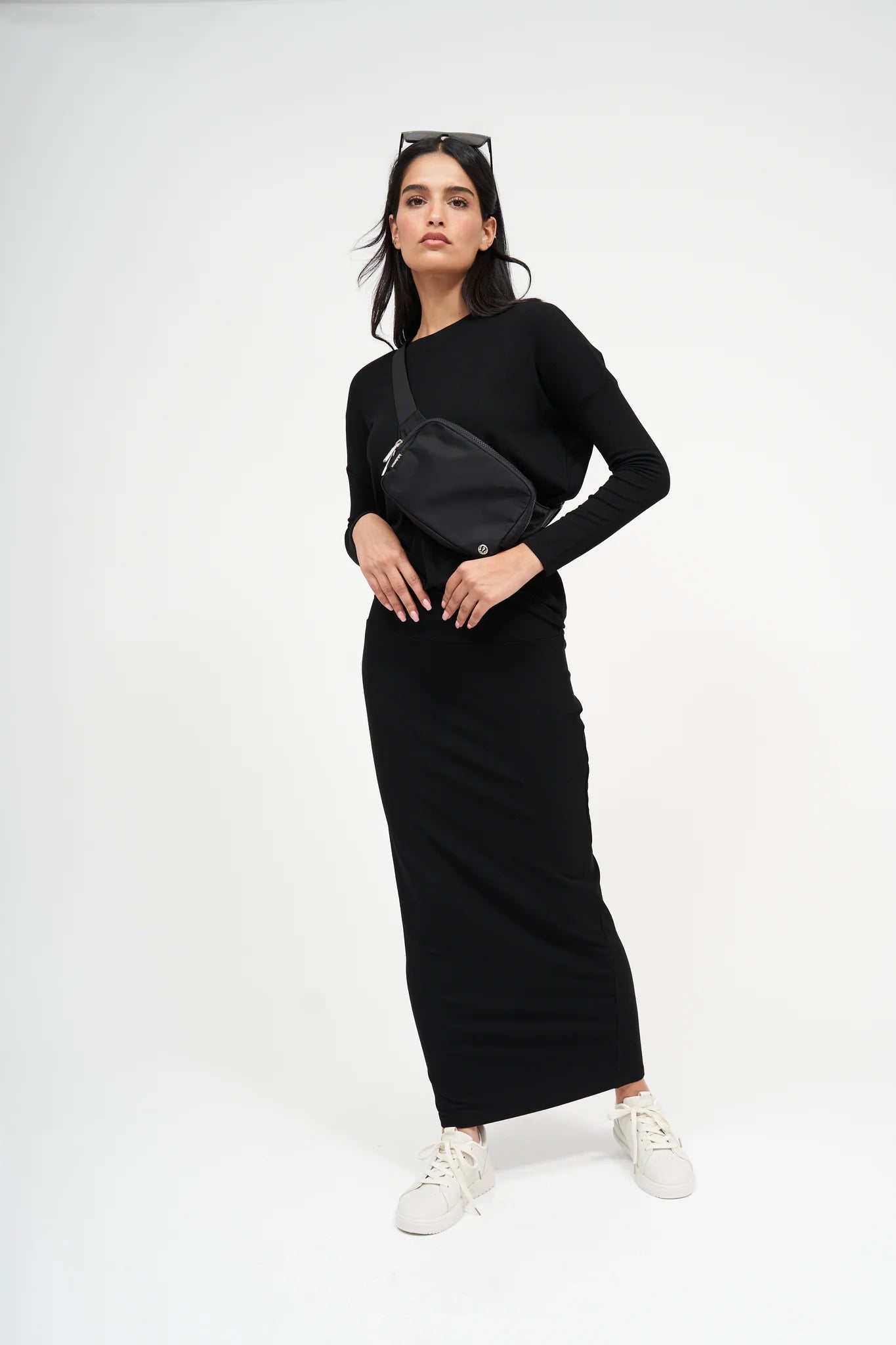 Woman wearing a black outfit with a belt bag on a white background